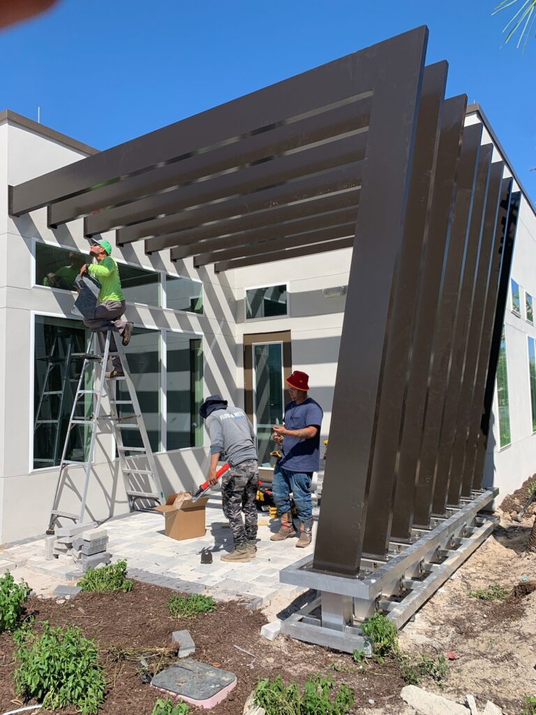 Bronze aluminum modern pergola installation in progress by Florida Outdoor Products.