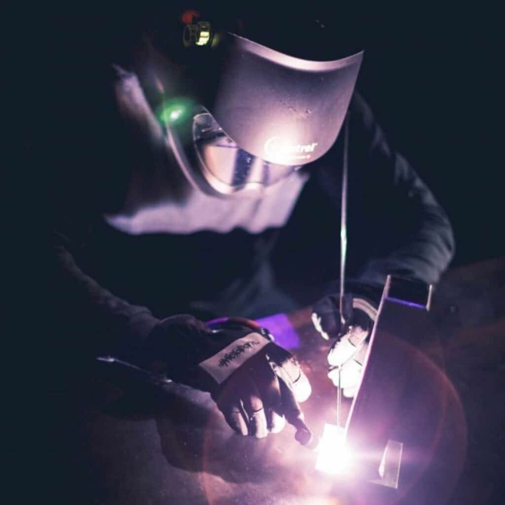 Skilled welder working with sparks flying in a dark background.